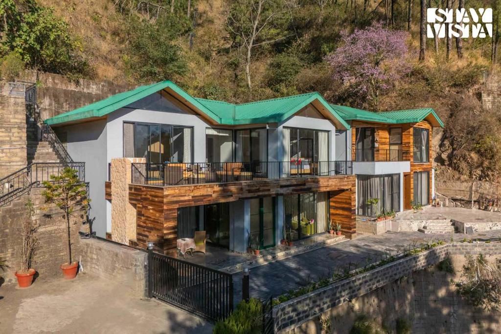 卡绍利StayVista at Thelma Cottage with BBQ & Bonfire的山上有绿色屋顶的房子