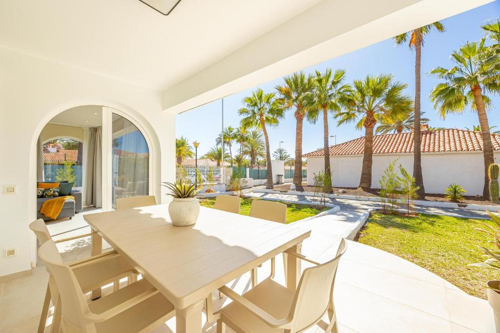 a dining room with a table and chairs and palm trees at LUXURY Sun Club 252 in San Bartolomé de Tirajana