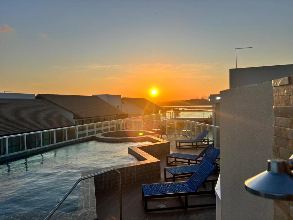 Sonnenuntergang in einem Gebäude mit Pool und Stühlen in der Unterkunft Flat Porto de Galinhas in Porto De Galinhas