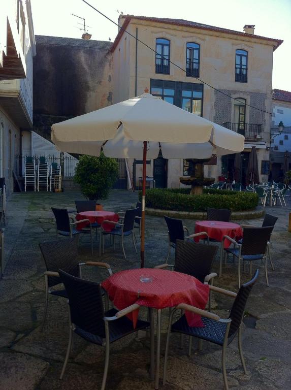 stół i krzesła z parasolem na dziedzińcu w obiekcie Hotel Pinzon w mieście Baiona