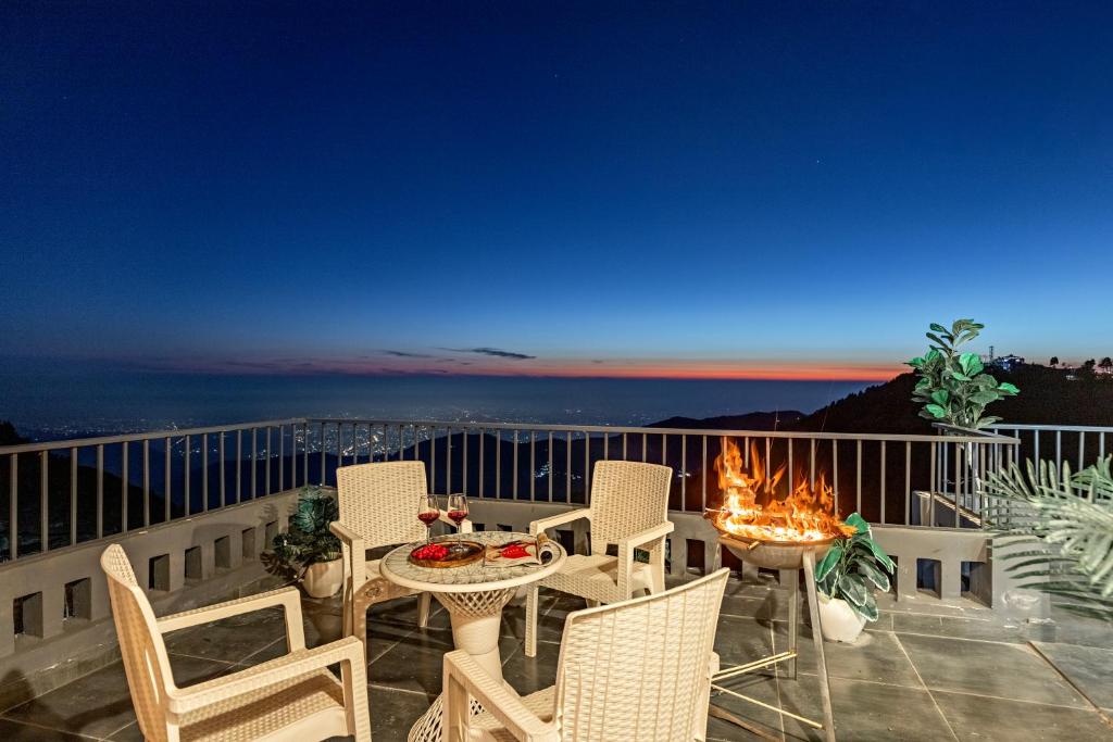 un patio avec une table et des chaises sur un balcon dans l'établissement Alaya Stays Evara - 2 BHK Hilltop Hideaway With Balcony, Fireplace & Scenic Views, à Mussoorie