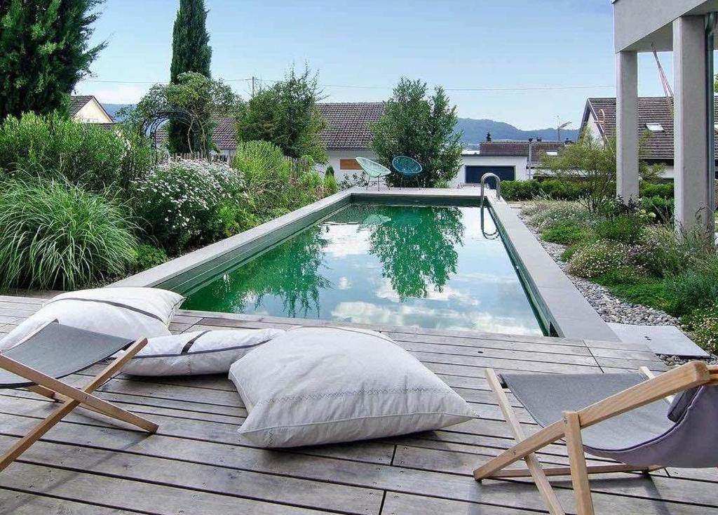 a swimming pool with pillows on a wooden deck at SeeSucht-Apartment No86 mit Terrassen, Sauna & Pool in Bodman-Ludwigshafen