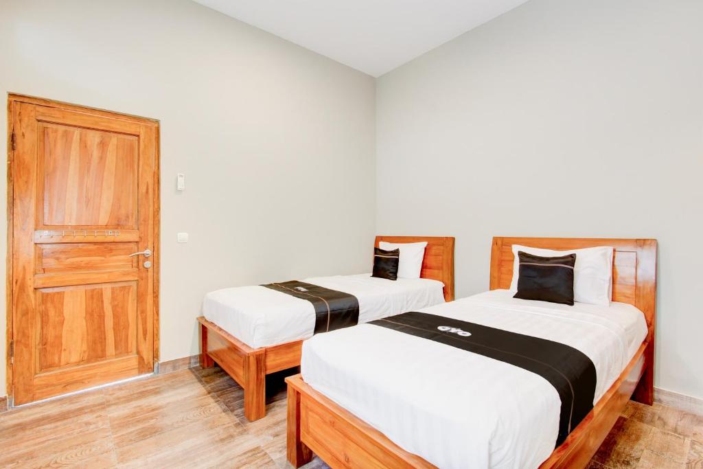 two beds in a room with a door at Capital O 94274 Homestay Balimoelih in Yogyakarta
