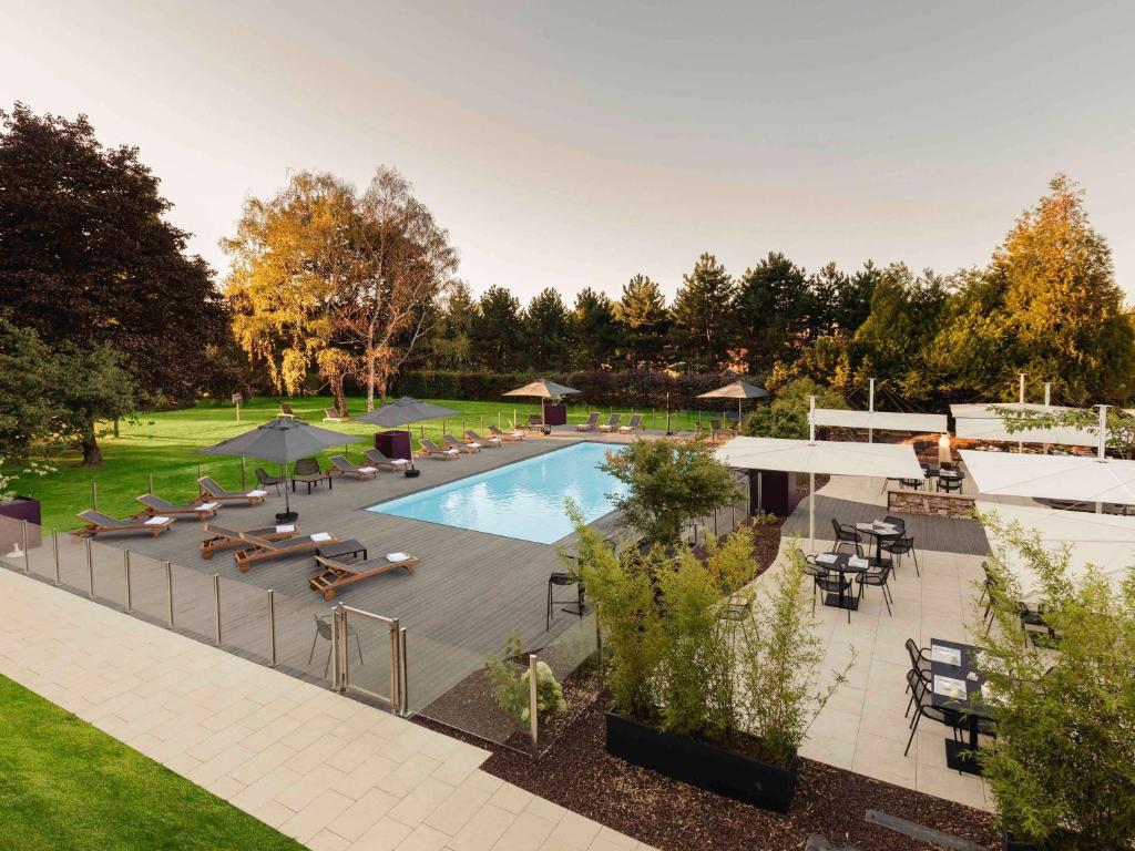 une vue aérienne d'une piscine avec des chaises et des parasols dans l'établissement Novotel Nancy, à Nancy