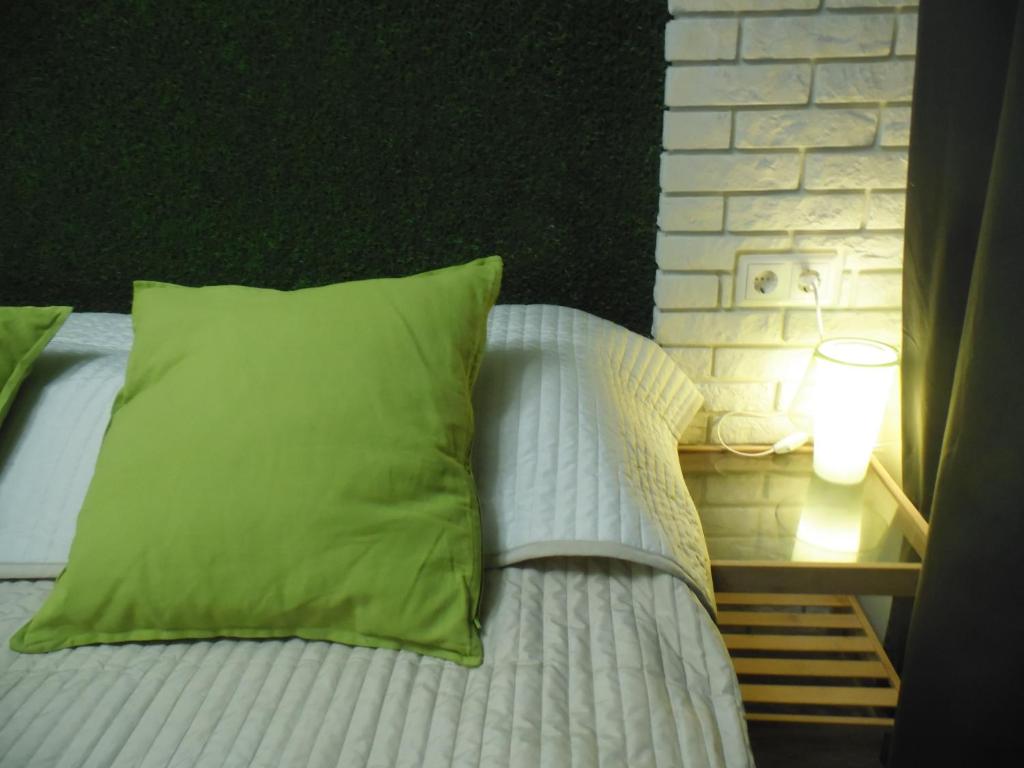 エカテリンブルクにあるBerloga on Cheluskintsevのベッド(緑の枕付)、テーブル(ランプ付)