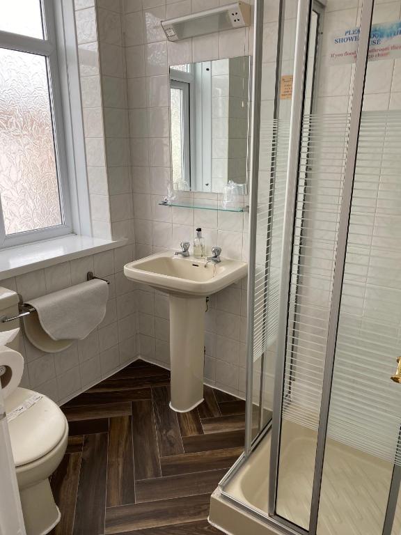 a white bathroom with a sink and a shower at The Arncliff Hotel in Blackpool