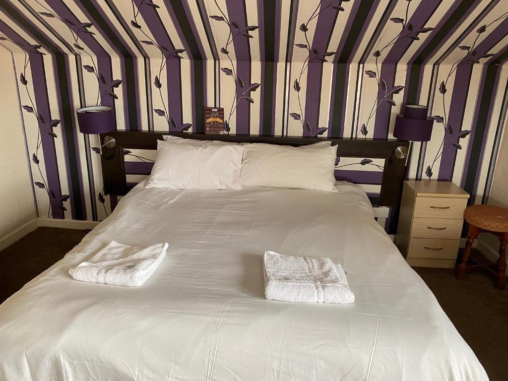a large white bed with two white towels on it at The Arncliff Hotel in Blackpool