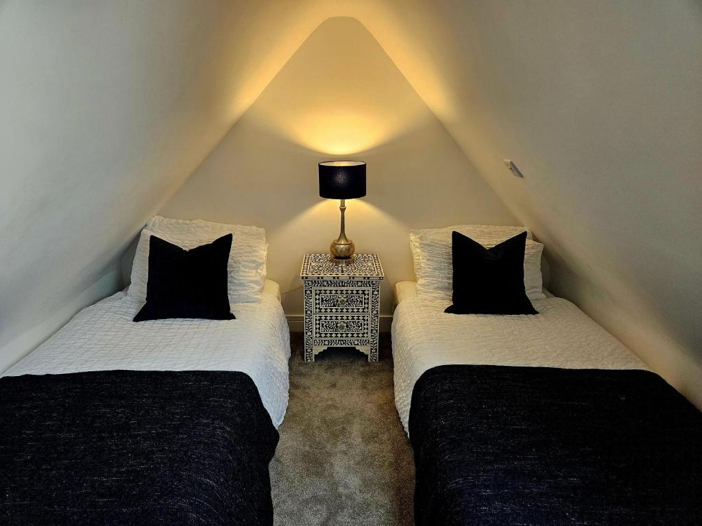 two beds in a attic with a lamp on a table at The Lodge in Wadhurst