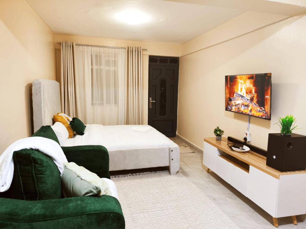 Un dormitorio con una cama, un sofá y un televisor. en R&R NAI-POSHA Studios, en Naivasha