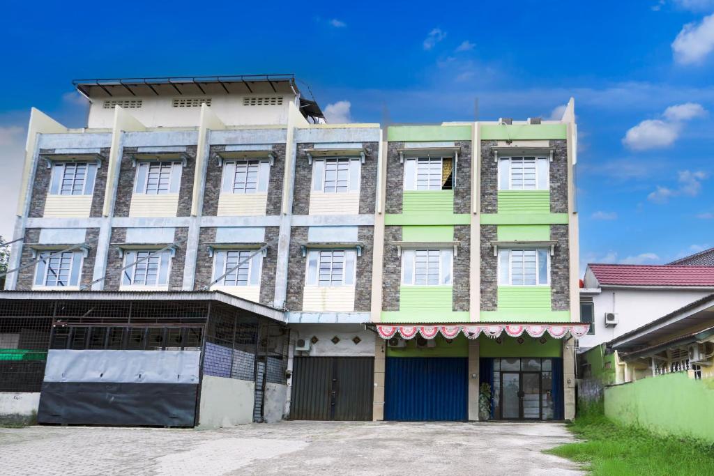 a green and white building with a lot of windows at Hotel O Ilir Timur I Near Rsud Siti Fatimah Az-Zahra Formerly Lumendiva Suite in Palembang