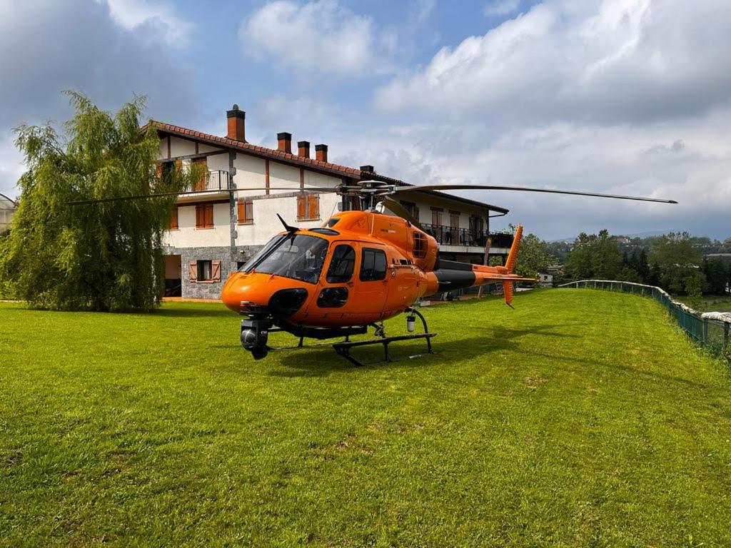 an orange helicopter parked in the grass in front of a house at casa rural larre aundi in Rentería