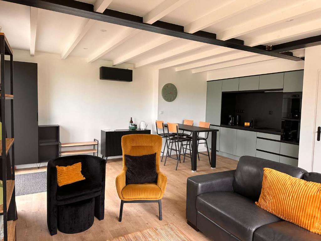 un salon avec un canapé et des chaises et une cuisine dans l'établissement La Grange d 'Arçais-sans linge de maison, à Arçais