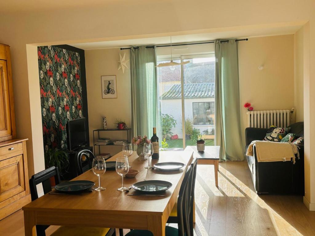 een eetkamer met een tafel met wijnglazen bij Maison proche centre ville et circuit avec jardin in Le Mans