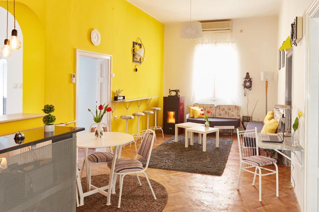 a living room with yellow walls and a table and chairs at Get Inn Skopje Hostel in Skopje