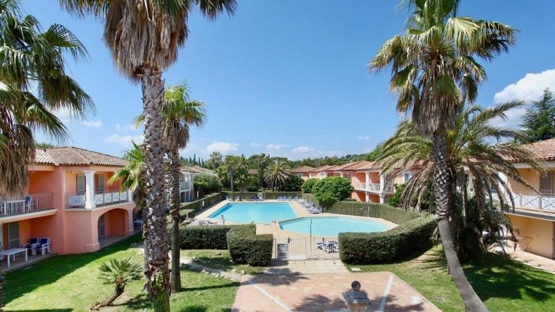 un complexe avec piscine et palmiers dans l'établissement Les Palmiers Appartement, à Grimaud