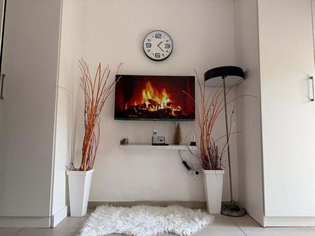 a living room with a fireplace and a clock on the wall at Dainfern Cozy Condo in Midrand