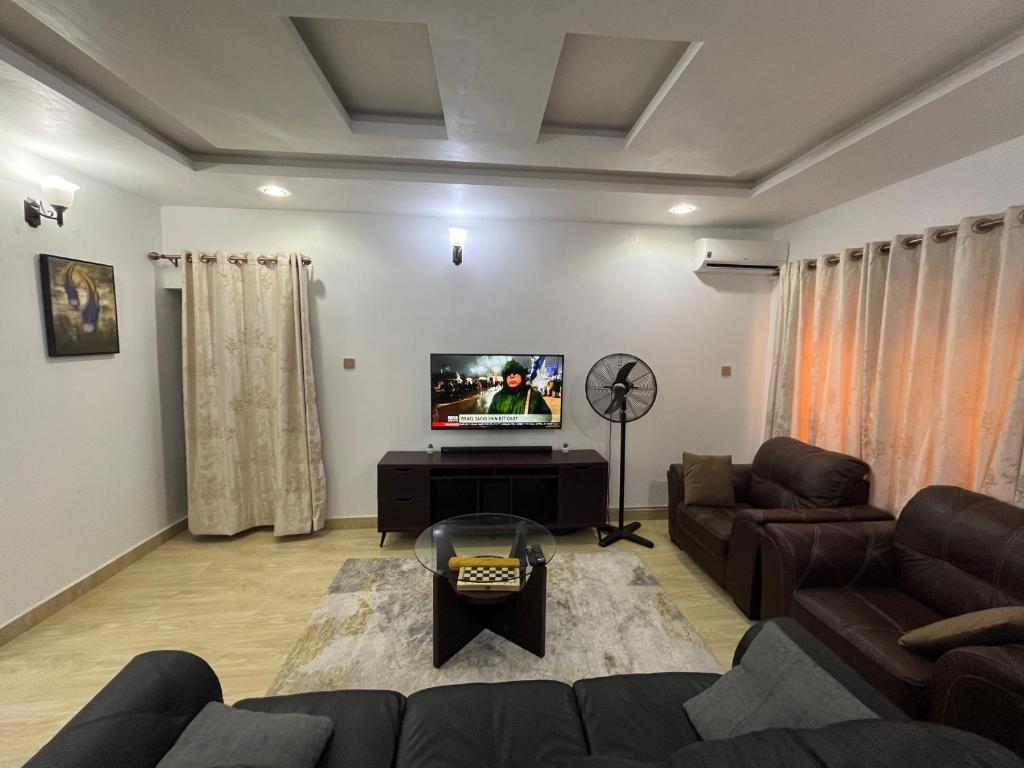 a living room with a couch and a flat screen tv at Feathers Apartments Abuja in Abuja