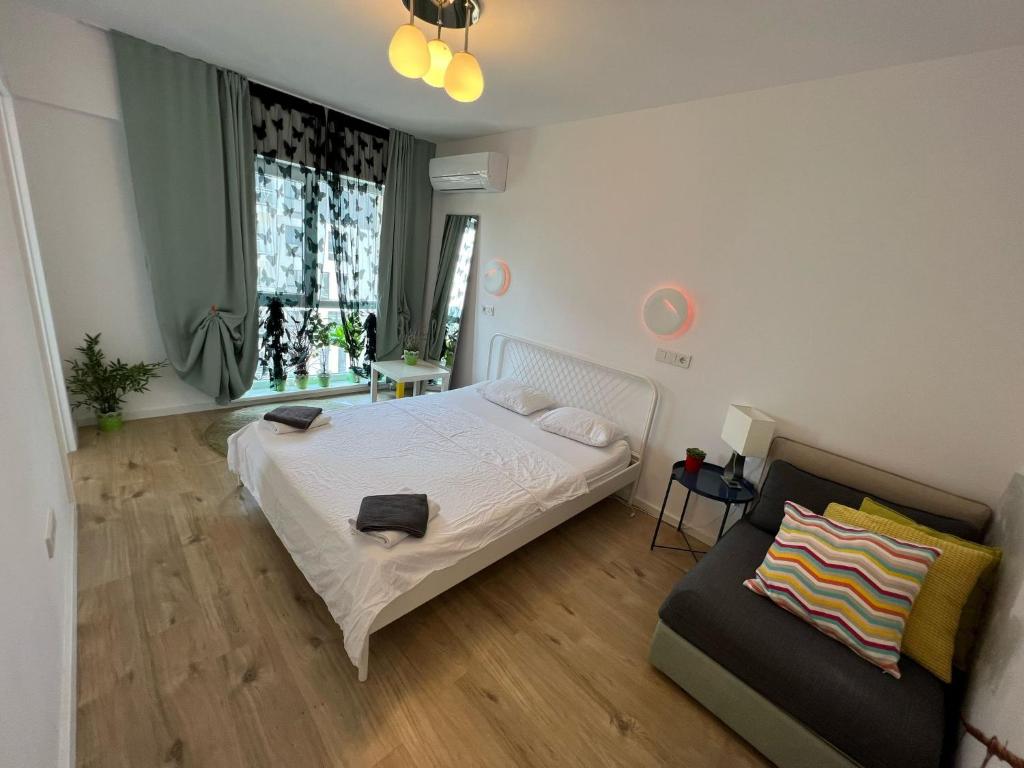 a bedroom with a white bed and a couch at Green apartments 109-5 with roof top view in Bucharest