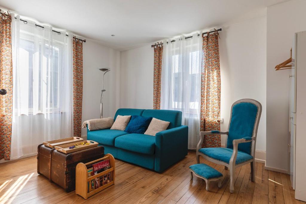 Una sala de estar con un sofá azul y una silla. en Le Seventies - Proche de Montbéliard, en Valentigney