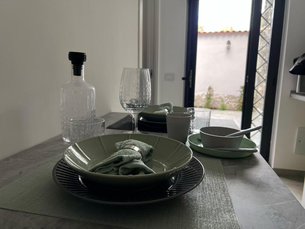 Una mesa con un cuenco y platos y una botella de vino. en Le Gioie di Monica Casa Vacanze per Pompei, en Boscotrecase