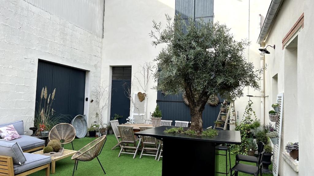 a patio with a table with a tree on it at NUANCES Gîte Simplicity and elegance 8-pers in Épernay