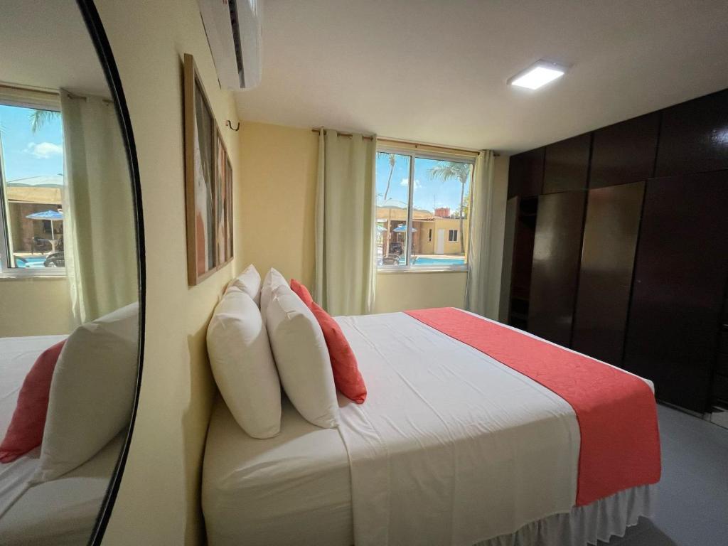 a bedroom with a bed with red and white pillows at Pousada e Restaurante Sal e Sol Cumbuco in Cumbuco