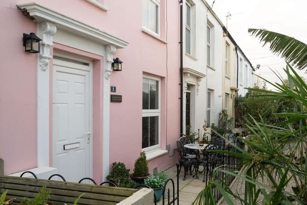a pink house with a table and chairs on a patio at Peaceful & Tranquil Cottage With Private Terrace at 'The Pink House' in Falmouth
