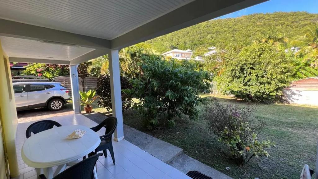 eine Veranda mit einem weißen Tisch und Stühlen und einem Auto in der Unterkunft Appartement confortable au Diamant avec terrasse privative - 40 m² in Le Diamant