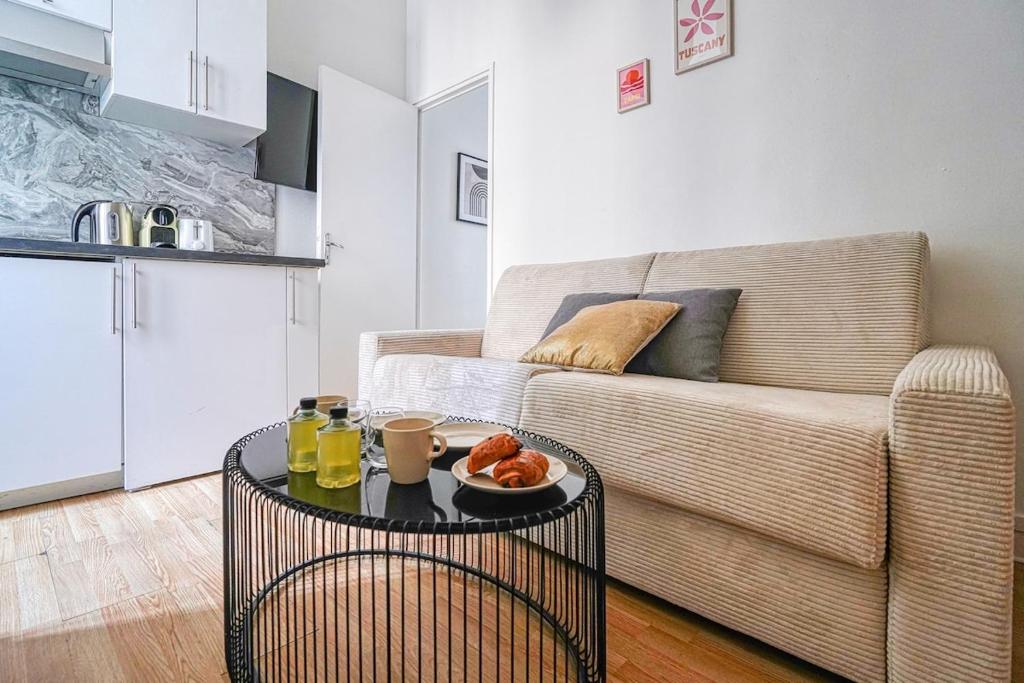 un salon avec un canapé et une table avec un bol de fruits dans l'établissement Appartement équipé quartier Montparnasse - X, à Paris