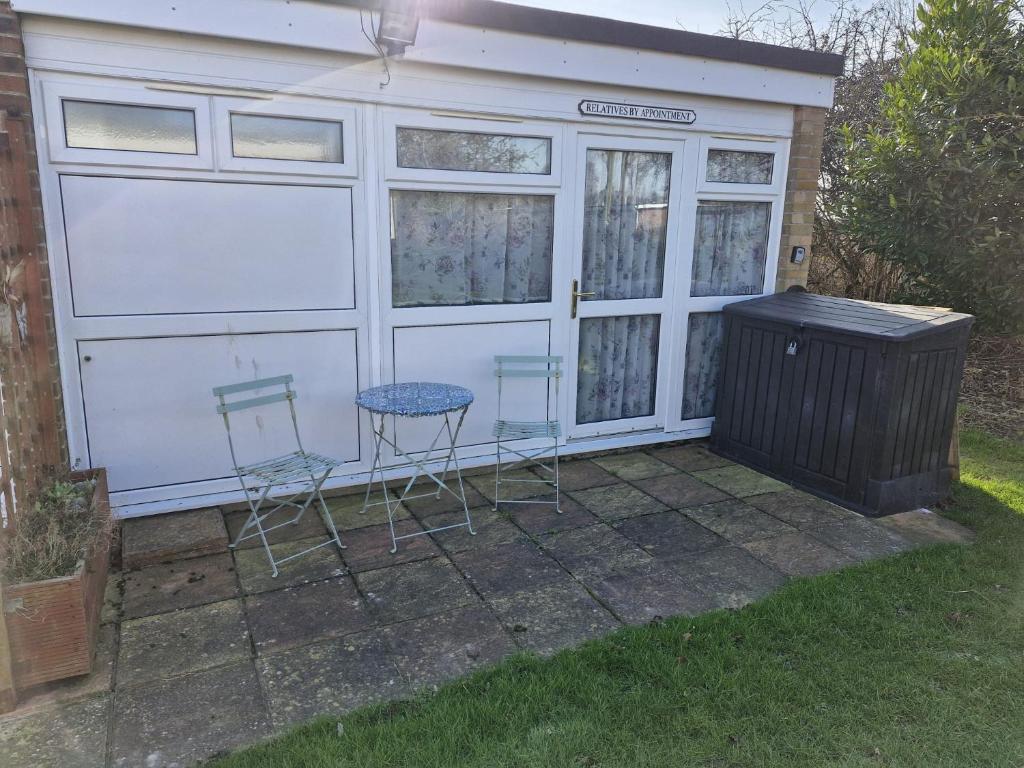 dos sillas y una mesa frente a un garaje en Parkview Retreat, en Hemsby
