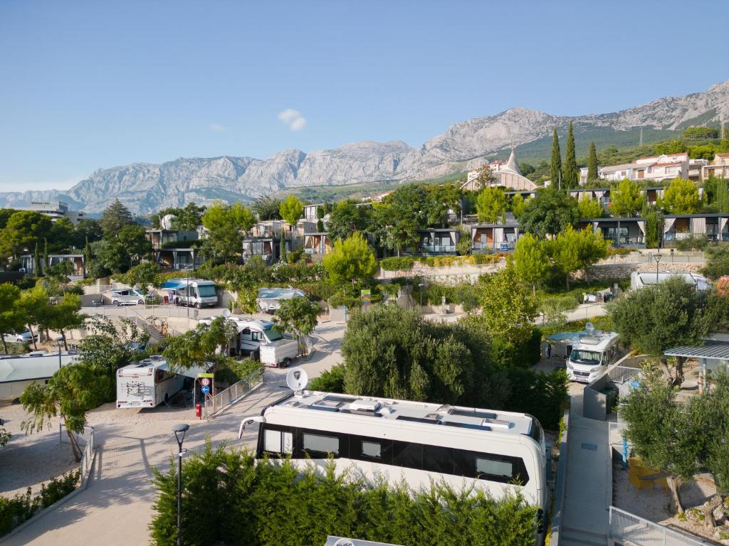 a bus parked in a parking lot with mountains in the background at Medora Orbis Camping Pitches in Podgora