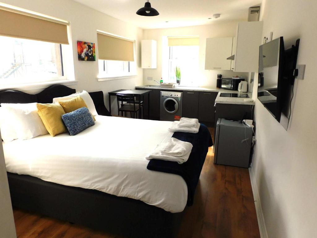 a bedroom with a large bed and a kitchen at No 3 - Modern Studio Apartment in Lanark Town Centre in Lanark