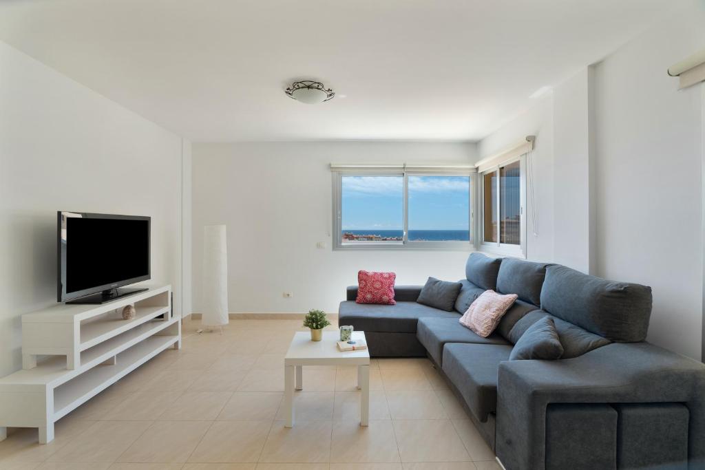 a living room with a blue couch and a tv at Tu Alojamiento En Playa Paraiso in Adeje