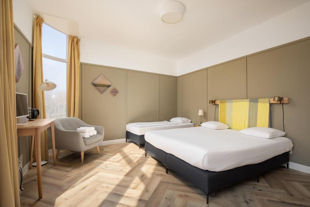 a hotel room with two beds and a chair at Hotel Light in Rotterdam