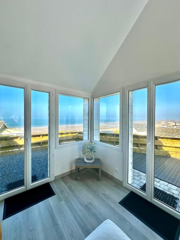 Cette chambre dispose de grandes fenêtres et d'une table. dans l'établissement Le perchoir avec vue mer, à 300m de la plage, à Saint-Côme-de-Fresné