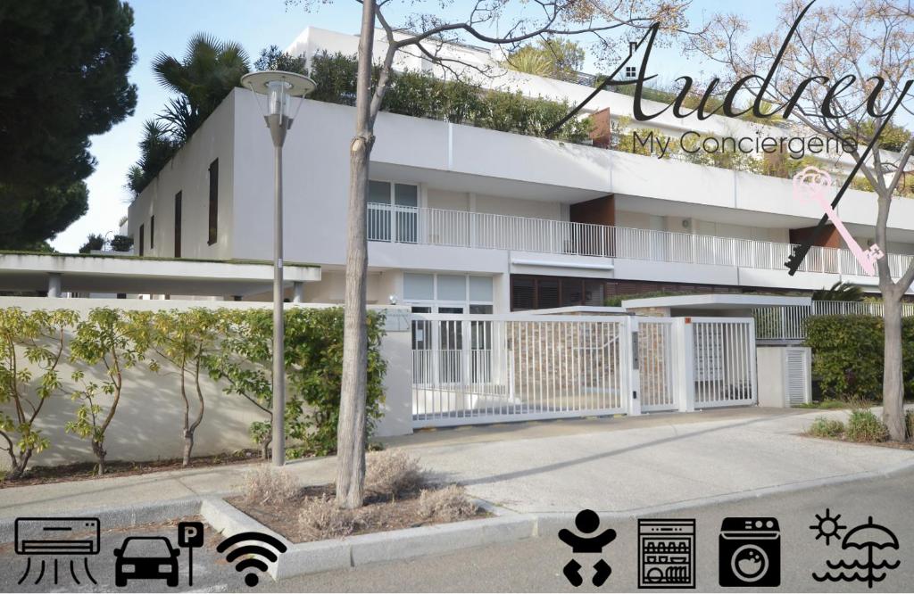 un bâtiment blanc avec une clôture blanche devant lui dans l'établissement Chez Martin - Spacieux appartement climatisé proche de la plage, à La Grande Motte