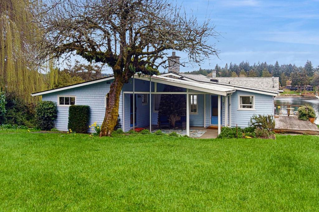 a small white house with a tree in a yard at Rosewater Cottage in Eagledale