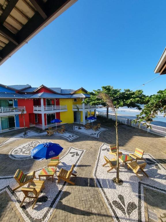 a group of chairs and an umbrella in a courtyard at Pousada Vila ÁguaMar in Itapoa