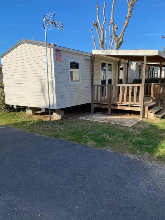 une petite maison avec un porche et une terrasse dans l'établissement Mobile home 4-6 places Camping les sables du midi Valras, à Sérignan