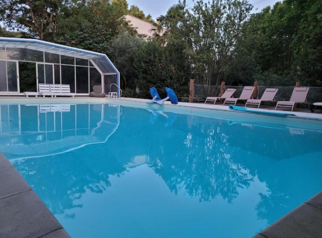 - une piscine avec des chaises et de l'eau bleue dans l'établissement Appartement les Acacias - campagne avec piscine commune - Eyragues, à Eyragues