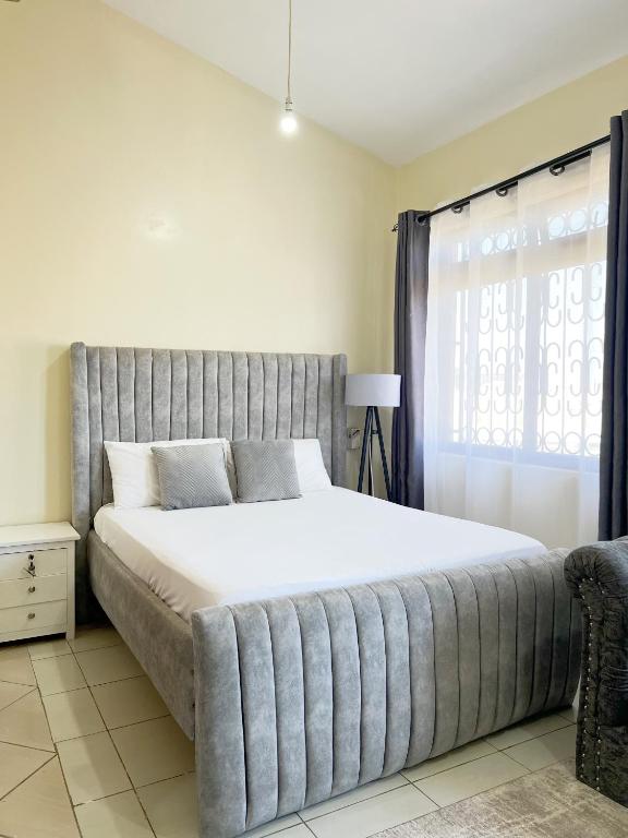 a large bed in a bedroom with a window at Caramel Home in Mombasa