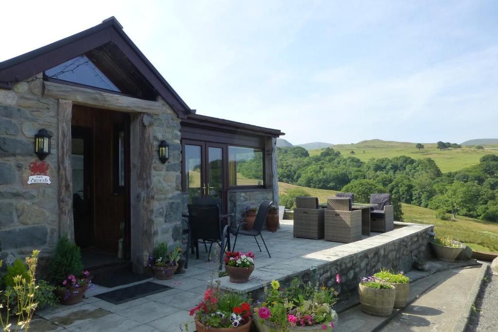 um chalé de pedra com um pátio com plantas e flores em Rhiwiau Guesthouse em Llanfairfechan