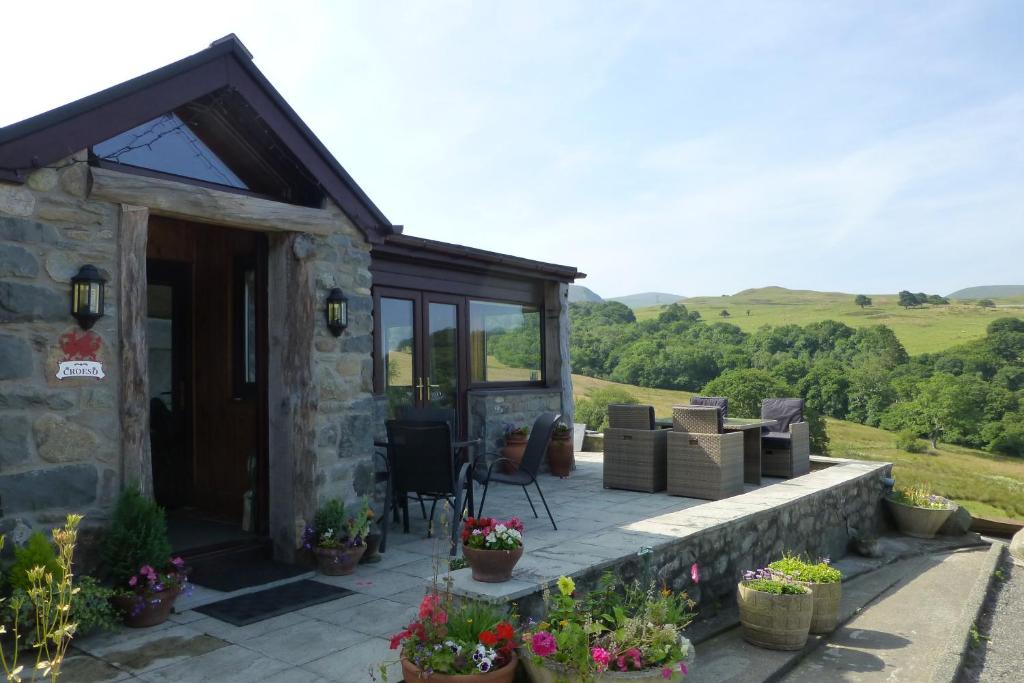 a stone cottage with a patio with plants and flowers at Rhiwiau Guesthouse in Llanfairfechan