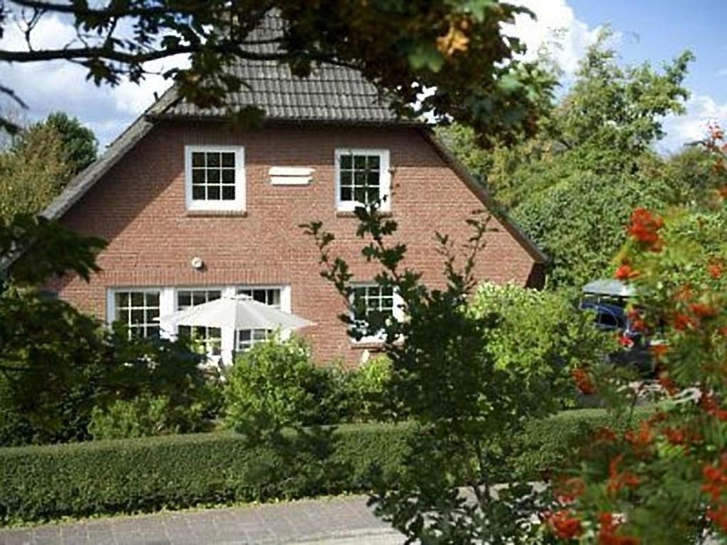 a red brick house with a white umbrella in front of it at Haus Heide "unten" in Borkum