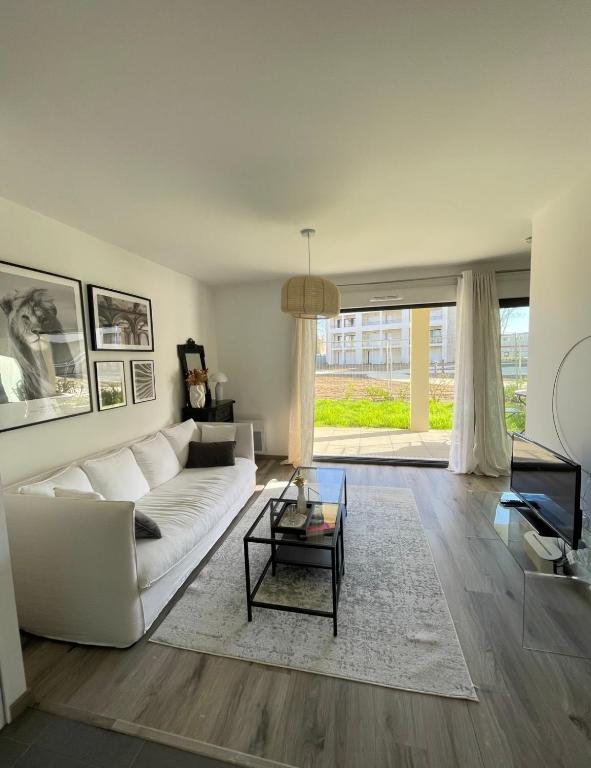 un salon avec un canapé blanc et une table dans l'établissement Sublime appart avec Jardin - 5 mn à pied des halles et plages, à Dinard