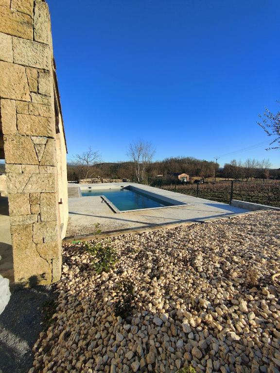 - un bâtiment en pierre avec une piscine dans une cour dans l'établissement Villa Olivia, Sud Ardèche, à Montréal