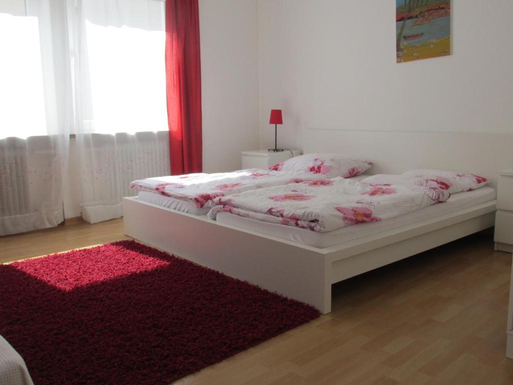a bedroom with a white bed with a red rug at Apartments Mayen in Mayen