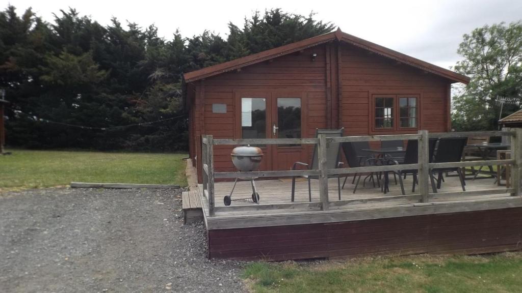 a small cabin with a deck and a grill at Spacious 3 bedroom cabin at Avonvale Holiday Lodge in Evesham