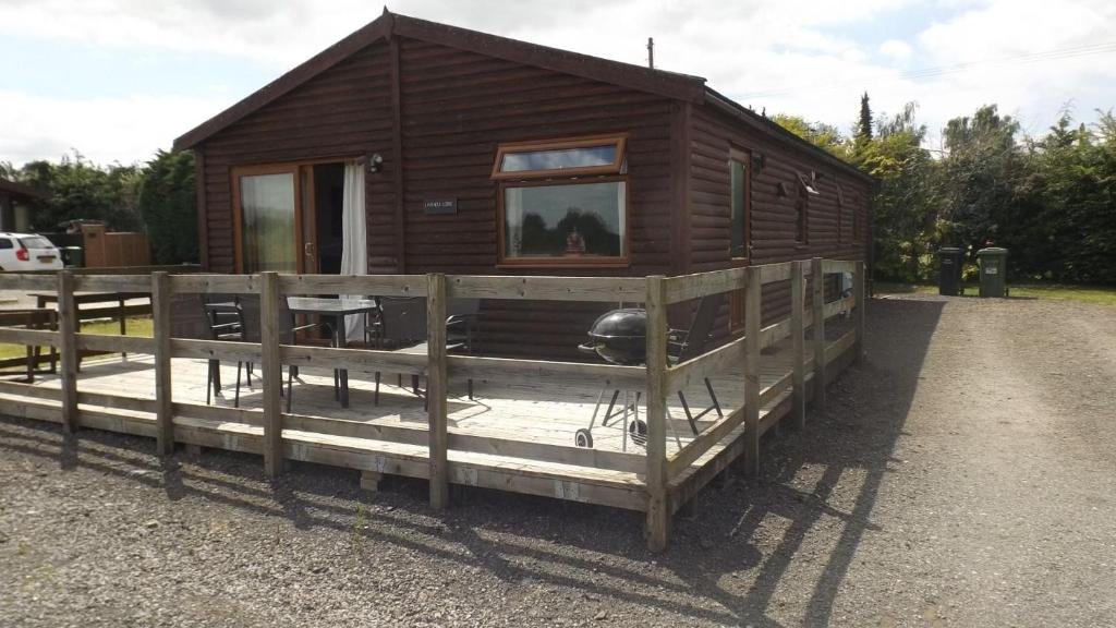 a small wooden cabin with a fence around it at Spacious 3 bedroom lodge at Avonvale Holiday Lodge in Evesham