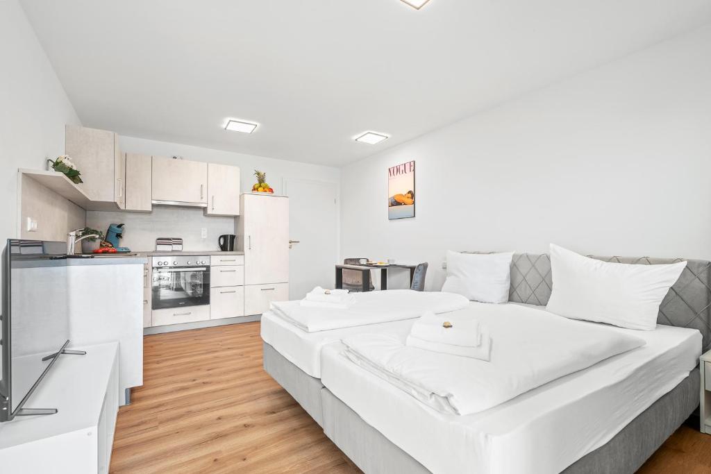 a white bedroom with a large bed and a kitchen at Stilvolles Apartment Bodensee A2 in Ravensburg